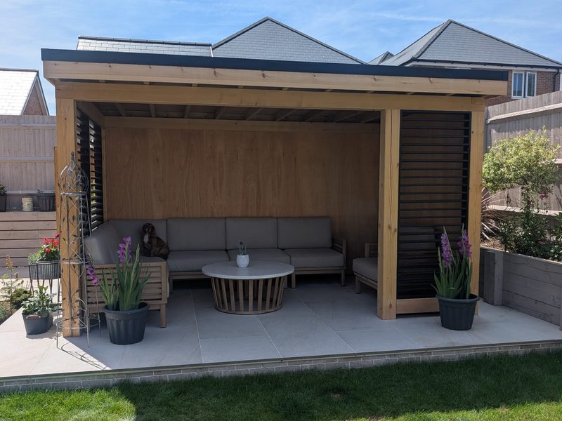 Garden room seating area with cushioned sofas on a porcelain patio